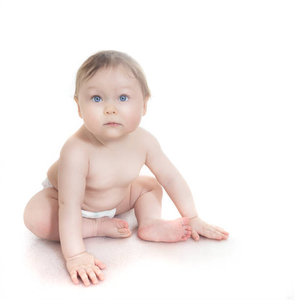 istock Small baby with blue eyes sitting on a white floor 650978824