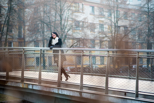 Smiling woman standing on the bridge and talking on the phone
