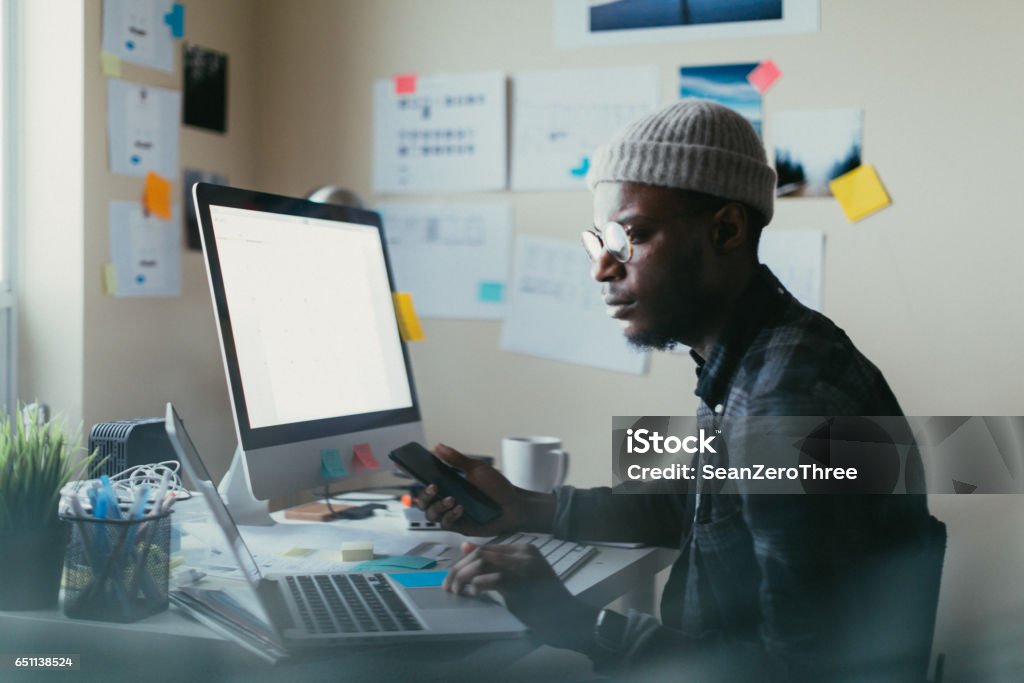 African American Man Working At His Desk Man in his 20s working at his desk on his computer. Computer Programmer Stock Photo