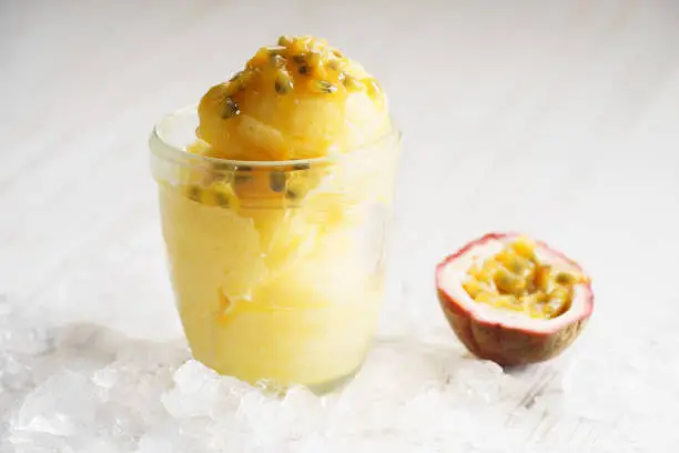 refreshing pineapple and passionfruit sorbet with ice on white wooden background
