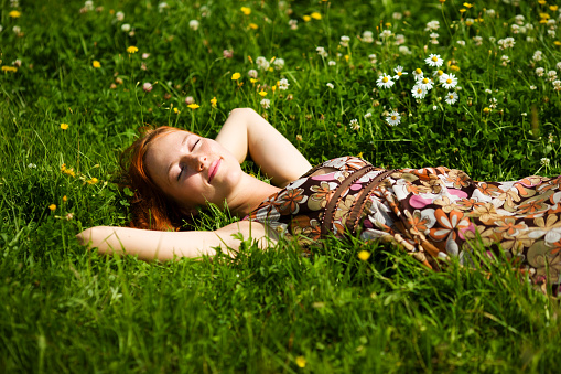 Young woman lying in grass dreaming summer day