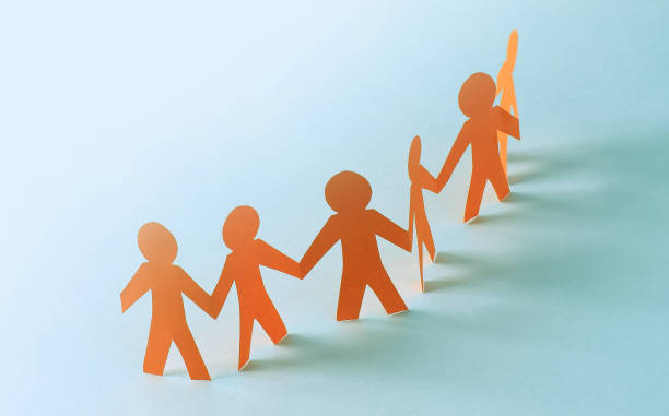 istock Team of paper doll people holding hands 651176482