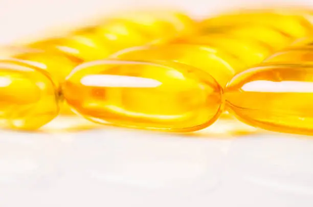 Pile of fish oil capsules over a white background