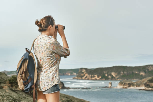 istock tourist with backpacker and binoculars in hands enjoying view coast on sunset. 651201946