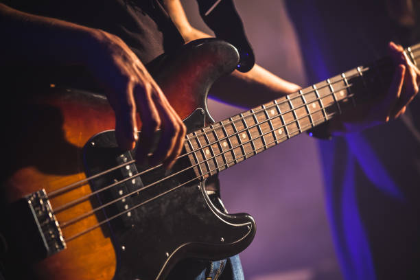 Close-up photo of bass guitar player Close-up photo of bass guitar player hands, soft selective focus, live rock music theme bass guitar stock pictures, royalty-free photos & images