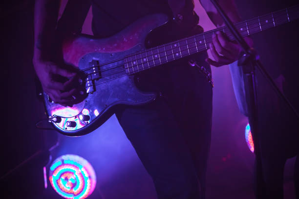 istock Electric bass guitar player in purple light 651209612