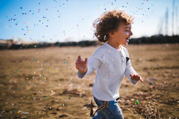 Young boy running at the beach with confetti