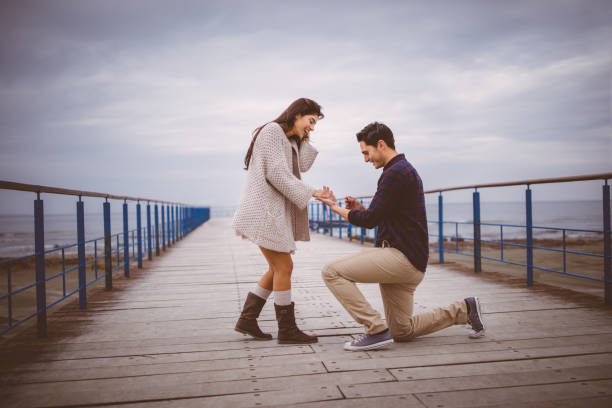 hombre en una rodilla, propone a la novia en un muelle - prometido fotografías e imágenes de stock