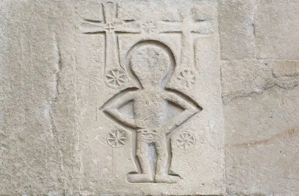 Photo of Relief with christian crosses and alien like person on wall of the 4th century Samtavro Church in Mtskheta, Georgia.