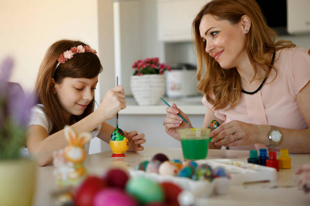 istock Happy mother with daughters painting Easter eggs at home 651230434