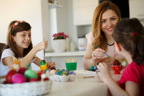 istock Happy mother with daughters painting Easter eggs at home 651230622