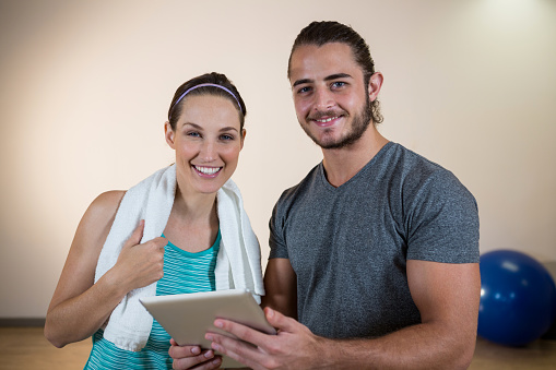 Portrait of fitness trainer and woman with digital tablet in fitness studio