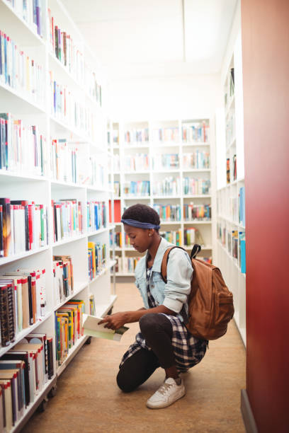 istock Schoolgirl selecting book from book shelf in library 651240530