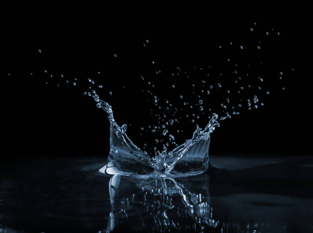 Splash on the water surface Clear, beautiful splash with drops on the water surface water on black surface stock pictures, royalty-free photos & images