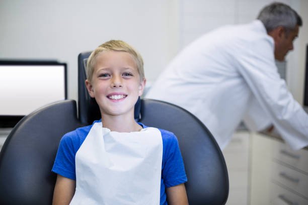 istock Smiling young patient sitting on dentist chair 651334310
