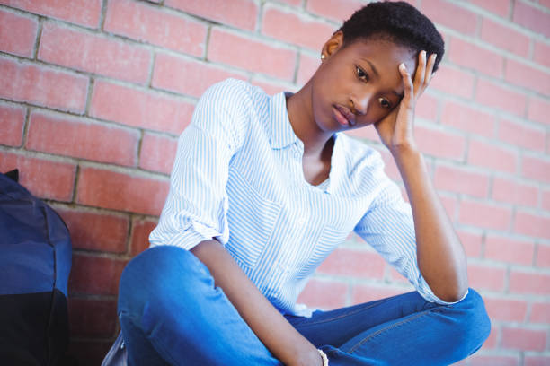 istock Sad schoolgirl sitting against brick wall 651335134