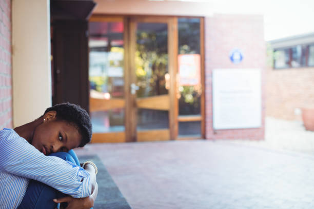 istock Sad schoolgirl sitting in school campus 651335368