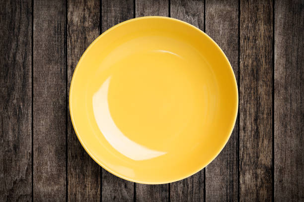 istock Simple yellow circular porcelain plate on wood with clipping path 651335458