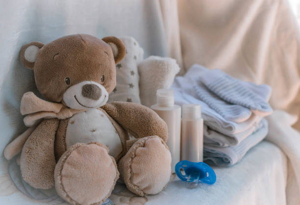 Stack of diapers with toy teddy bear and bottle of milk. Set for kid, baby shower, copy space, flat lay