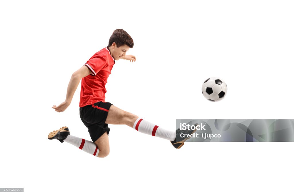 Teenage soccer player kicking a football Teenage soccer player kicking a football isolated on white background Soccer Player Stock Photo