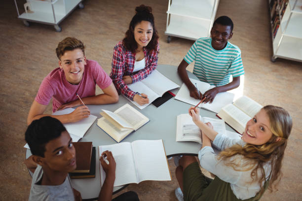 istock High angle view of happy classmates studying in library 651353272