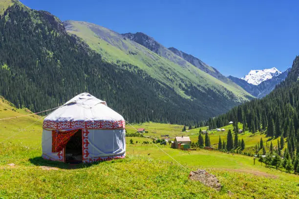 Beautiful mountain landscape with the white Yurt, decorated with a red ornament, Kyrgyzstan.