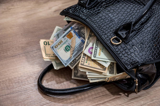 czarna torebka kobieta pełna pieniędzy, na biurku. - wallet wealth bill one hundred dollar bill zdjęcia i obrazy z banku zdjęć