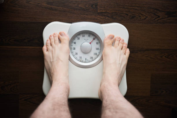 una persona è in piedi su una scala di peso o bilance per controllare il peso corporeo - emaciated weight scale dieting overweight foto e immagini stock