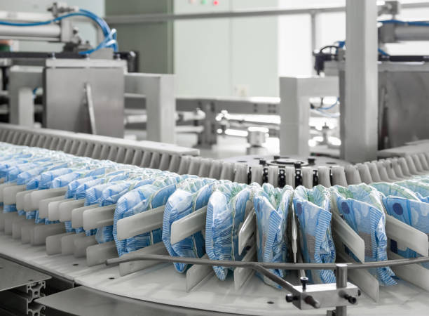 plant for the production of diapers diapers on a conveyor belt closeup. factory and equipment for the production of pampers manufacturing diapers stock pictures, royalty-free photos & images