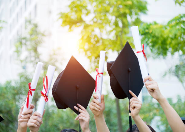 istock Graduates holding motarboards and diplomas 651455484