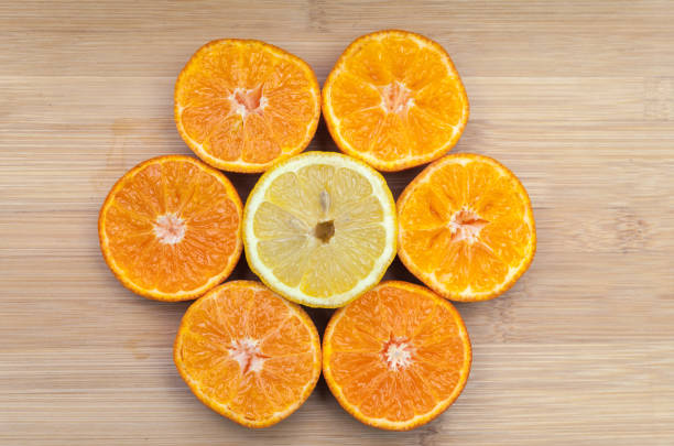 Directly above shot of halved oranges surrounding lime on wooden table