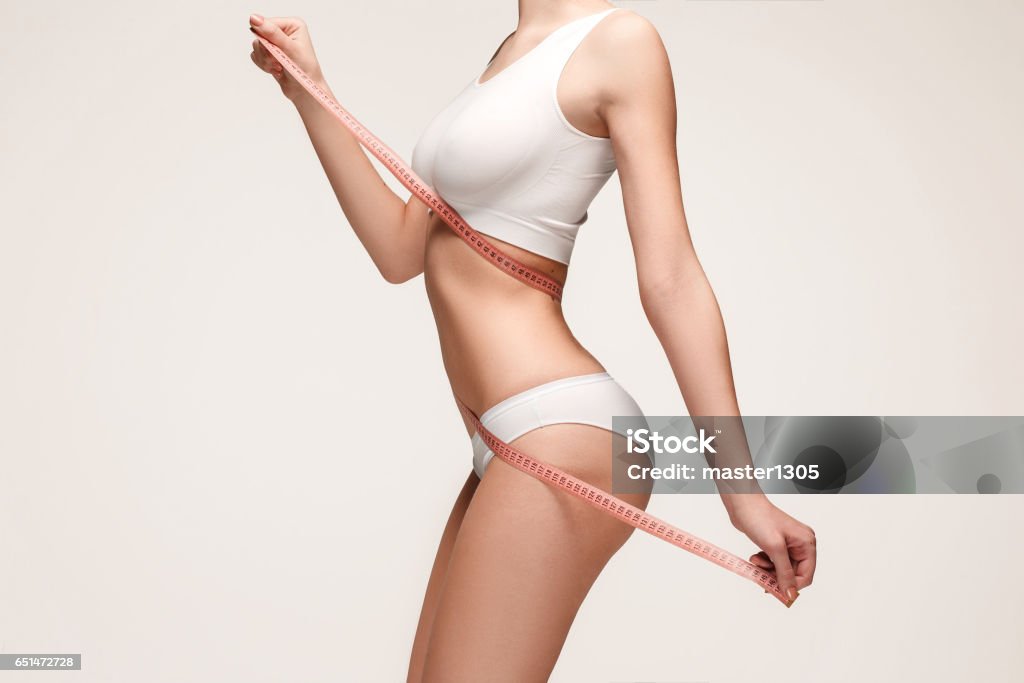 The girl taking measurements of her body, white background The girl taking measurements of her body, white studio background. The Human Body Stock Photo