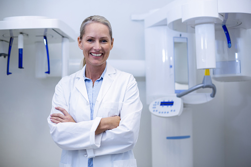 Portrait of female dentist smiling with arms crossed in dental clinic