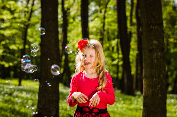 istock lovely blond girl playing with soap bubbles 651492292