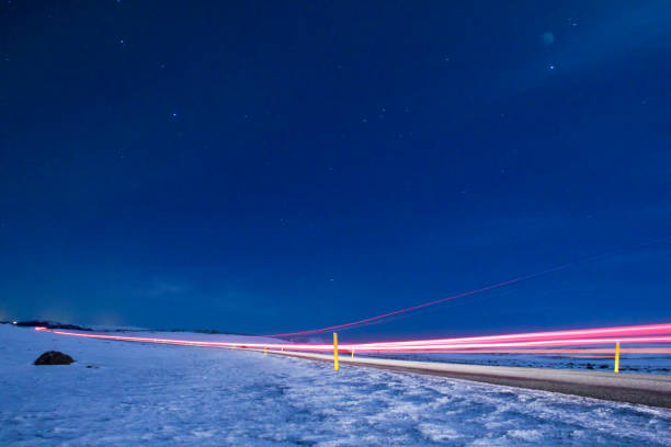 istock Long exposure car's light driving on highway surrounded by snow 651498940