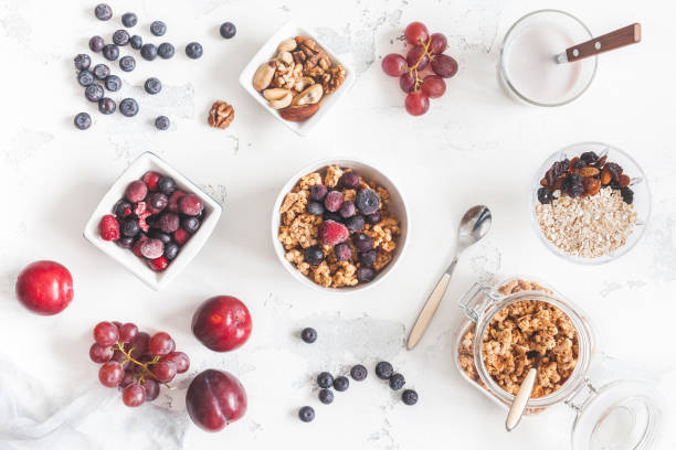 Breakfast with muesli, fruits, yogurt, frozen berries, nuts Breakfast with muesli, fruits, yogurt, frozen berries, nuts on white background. Healthy food concept. Flat lay, top view frozen grapes stock pictures, royalty-free photos & images