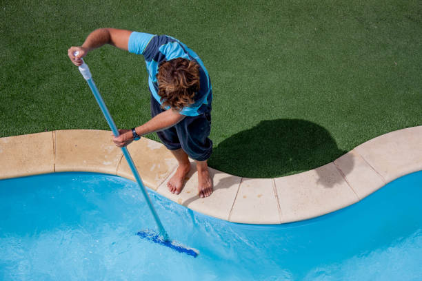 Male pool cleaner cleaning a blue pool Pool guy celaning a pool with vacuum cleaner pole photos stock pictures, royalty-free photos & images