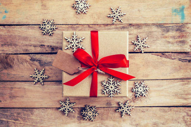 istock Brown gift box and snowflakes on wooden background. 651523034