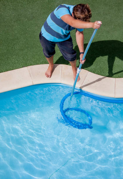 istock Male pool cleaner cleaning a blue pool 651547304