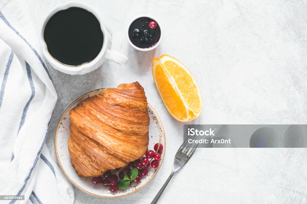 Croissant with coffee, jam and fruits top view Continental breakfast with fresh croissant, berries, jam, black coffee and orange wedge on a table. Top view, copy space for your text Breakfast Stock Photo