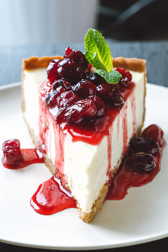 New York cheesecake with cherry sauce and mint leaf. Closeup view, selective focus