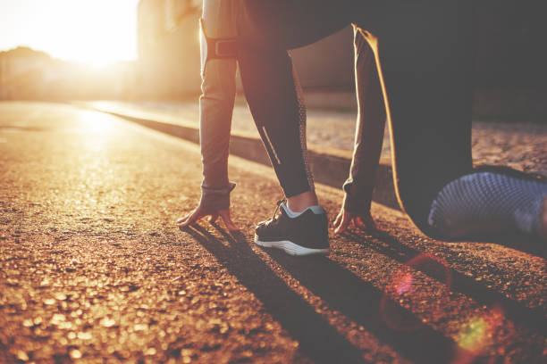 Athlete woman in running start pose Athlete woman in running start pose on the city street. Sport tight clothes. Bright sunset, blurry background. Horizontal runner on start pose stock pictures, royalty-free photos & images
