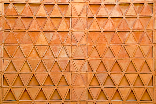 Terra cotta tile wall composed of triangle shapes.