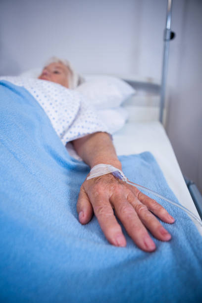 istock Senior patient hand with saline on bed in hospital 651646548