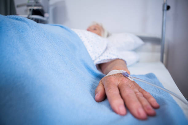 istock Senior patient hand with saline on bed in hospital 651646584