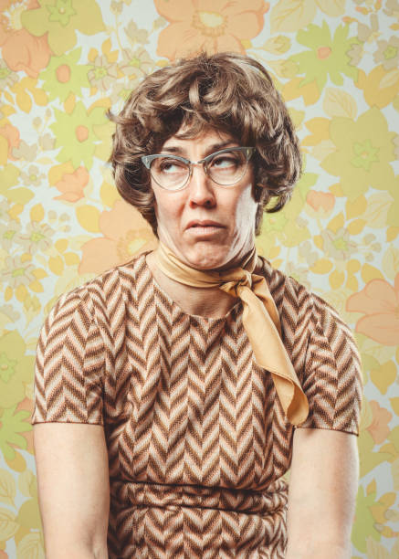 Adult Woman Retro Seventies Style A portrait of a woman in 1970's style, posing in front of a vintage floral wallpaper background.  She has a look of boredom or disgust on her face. rolling eyes stock pictures, royalty-free photos & images