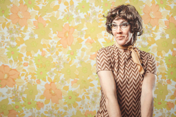 Adult Woman Retro Seventies Style A portrait of a smiling, cheerful woman in 1970's style, posing in front of a vintage floral wallpaper background.  Horizontal with copy space. kitsch photos stock pictures, royalty-free photos & images