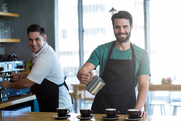 istock Smiling waiter making cup of coffee at counter in cafe 651756766