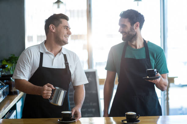 istock Smiling waiter interacting while making cup of coffee at counter 651756804