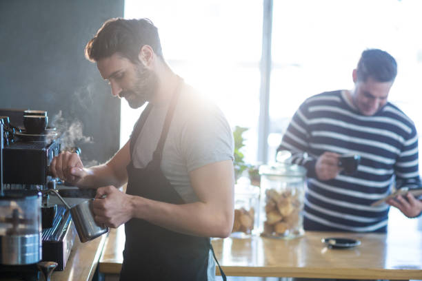 istock Smiling waiter making cup of coffee 651757330
